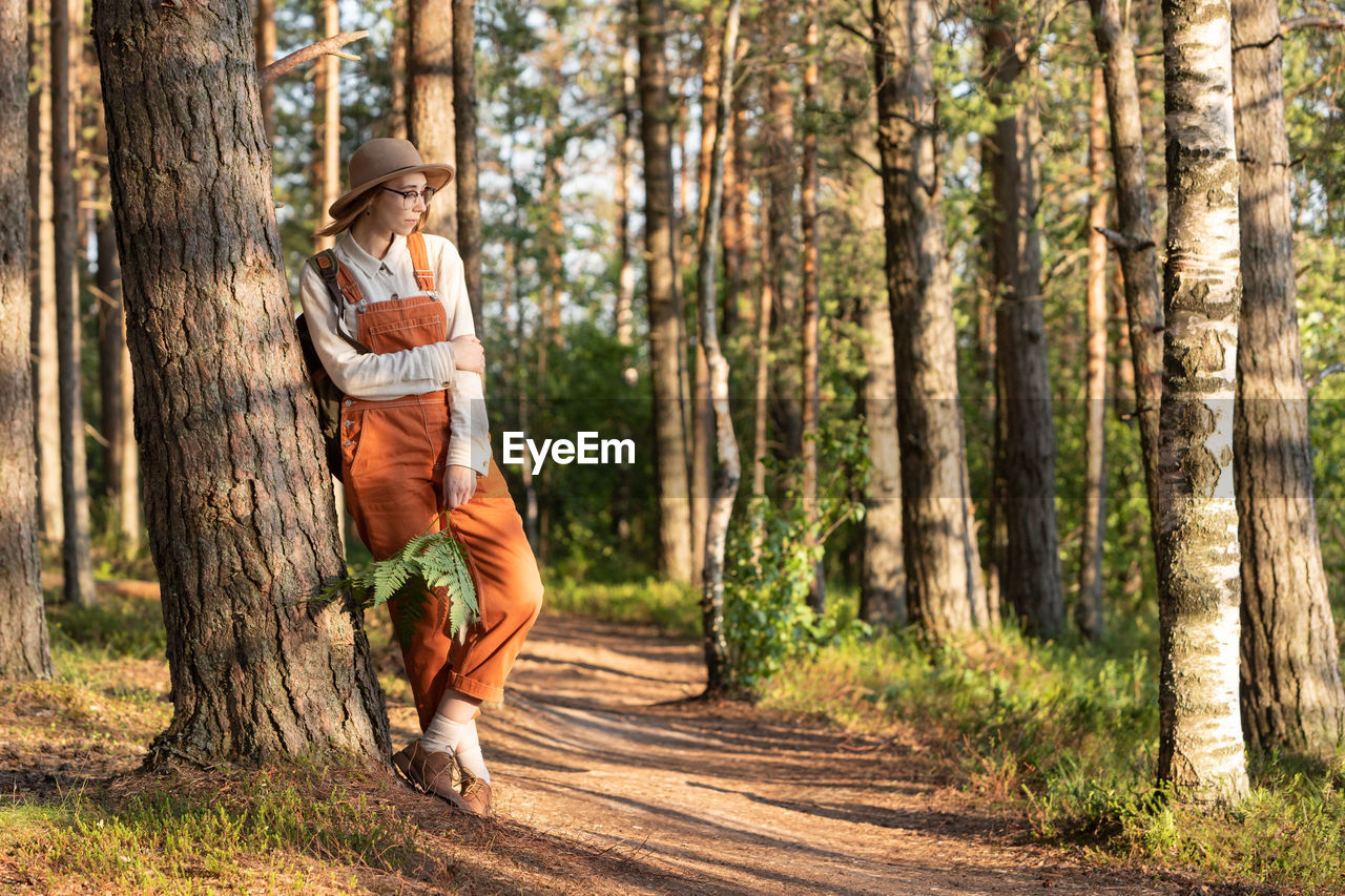 Woman botanist with backpack on ecological hiking trail in forest. naturalist exploring wildlife