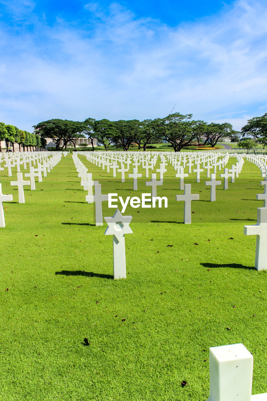 Cross on grassy field at cemetery