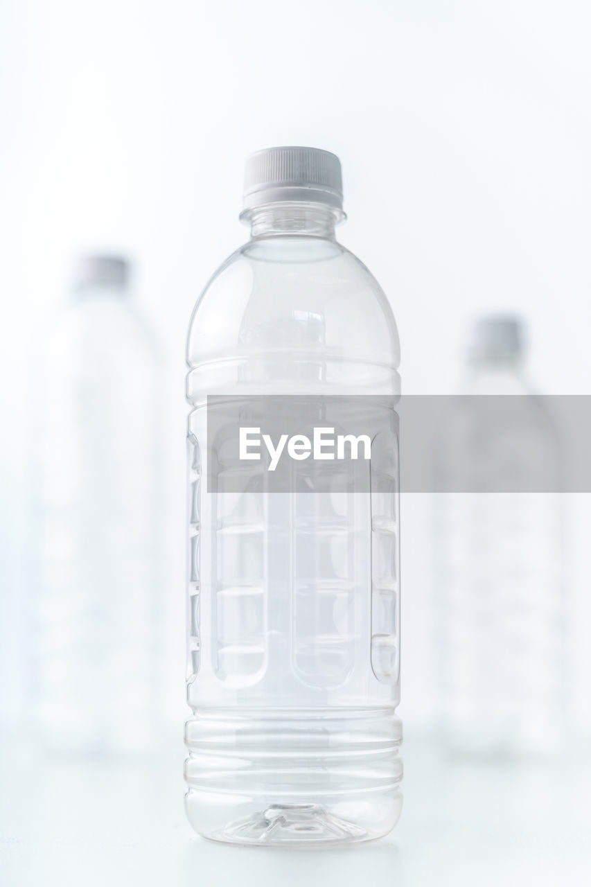 Close-up of clear plastic bottles against white background