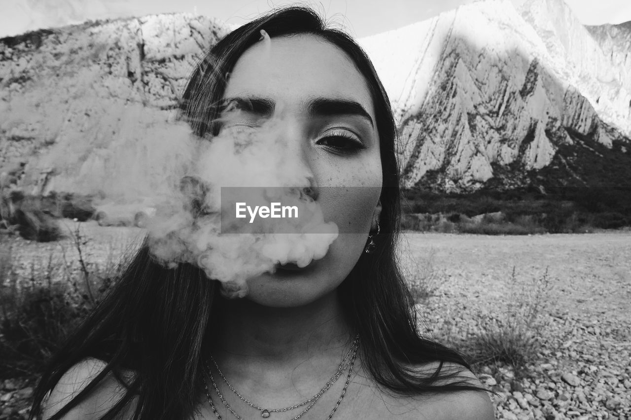 Close-up portrait of teenage girl smoking against snowcapped mountains