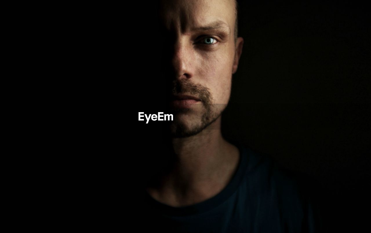 Close-up portrait of man against black background