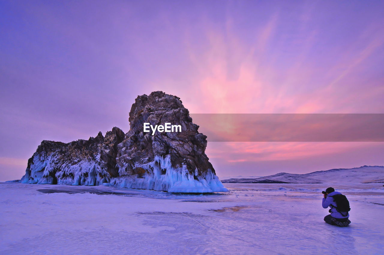 Man photographing rock formation during winter