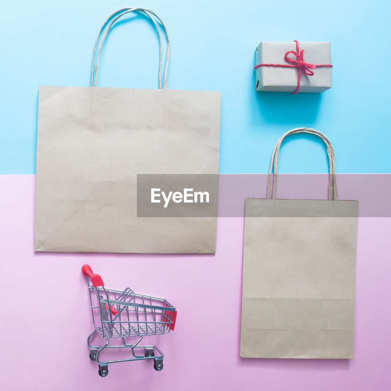 Close-up of shopping bags with shopping cart and gift on table