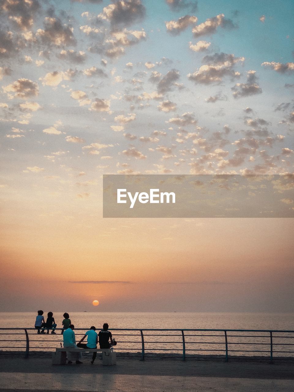 People on beach against sky during sunset