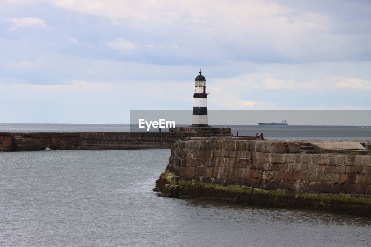 LIGHTHOUSE BY SEA AGAINST SKY AND BUILDINGS