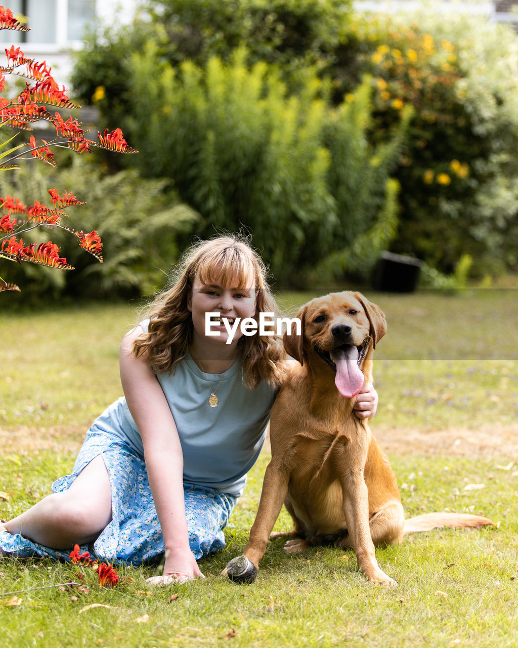 portrait of young woman with dog on grassy field