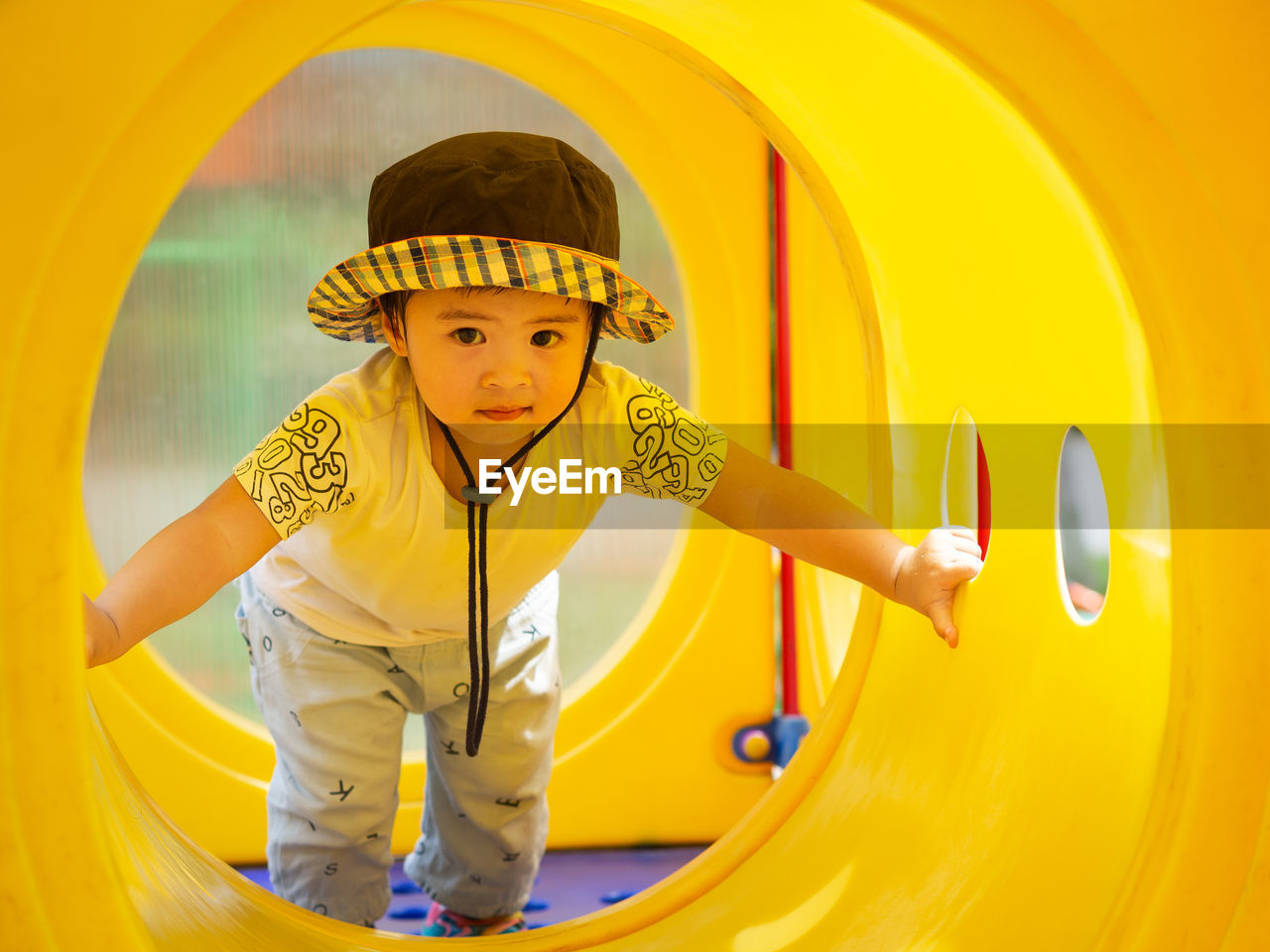 PORTRAIT OF CUTE BOY ON YELLOW PLAYGROUND