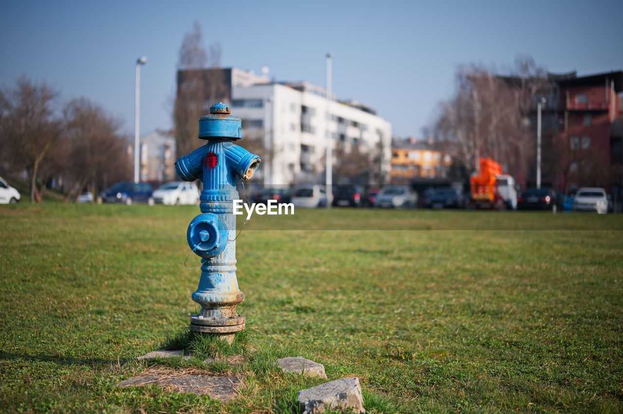 Traditional blue water pump with cityscape in background