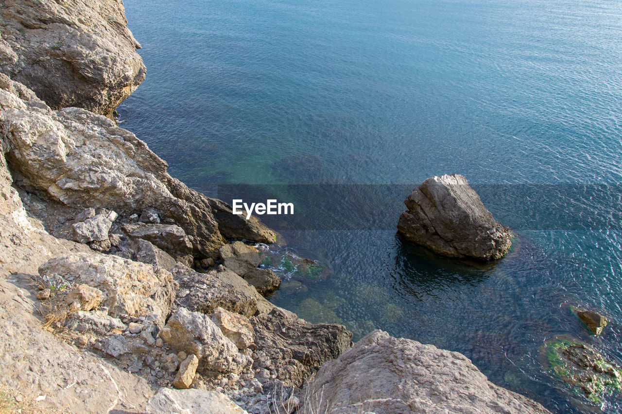 HIGH ANGLE VIEW OF ROCK FORMATIONS AT SEA