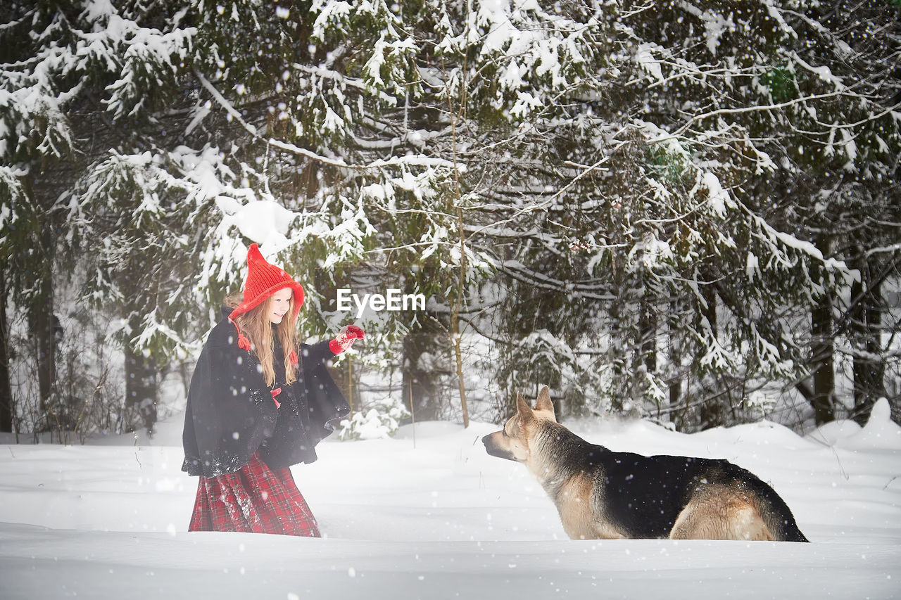 rear view of woman with dog on snow covered field