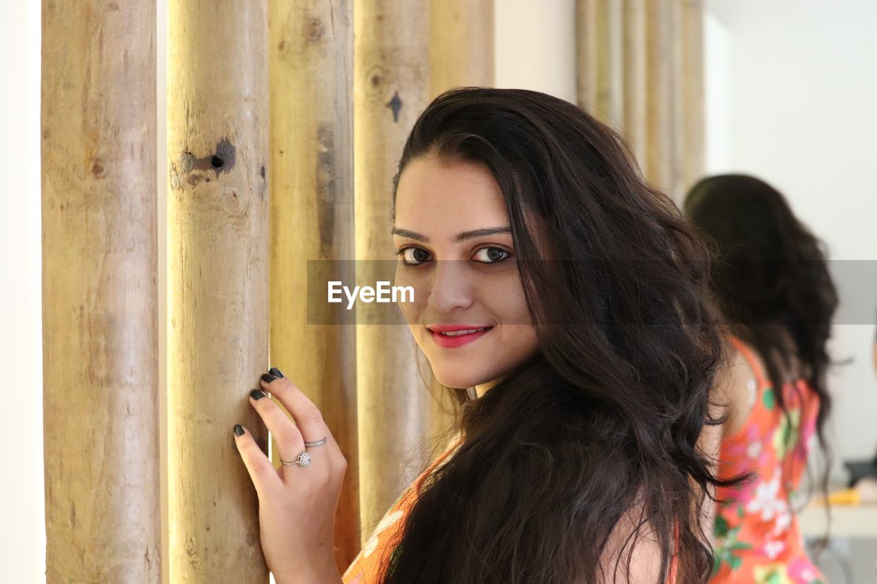 Portrait of a beautiful young woman against mirror