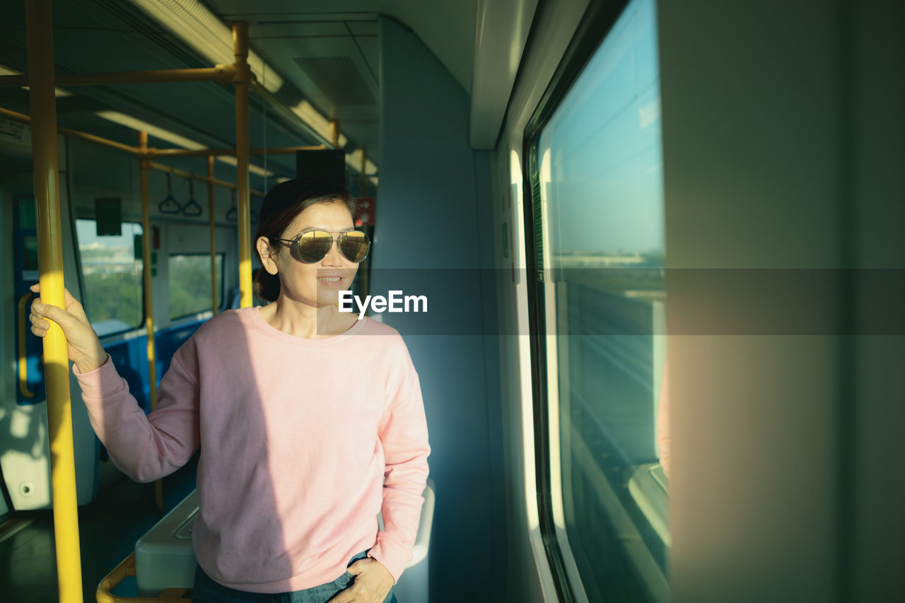 Smiling woman in sunglasses standing at train