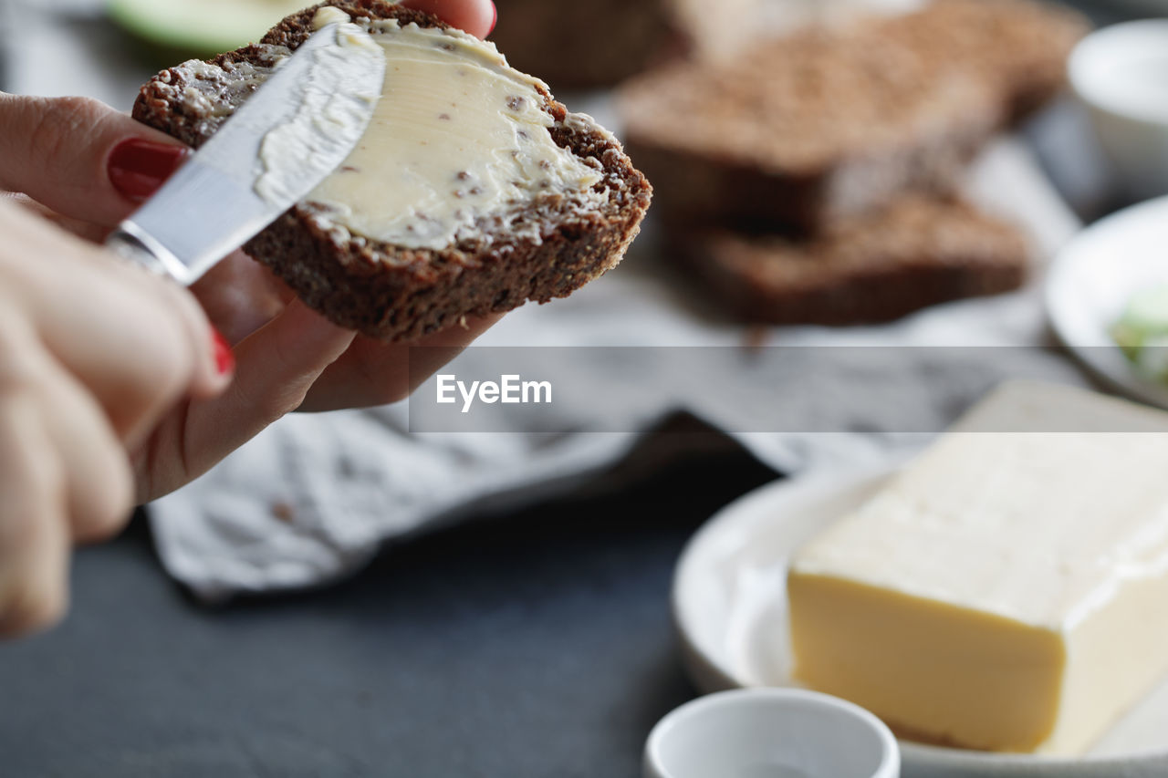 Cropped image of woman hand applying butter on bread