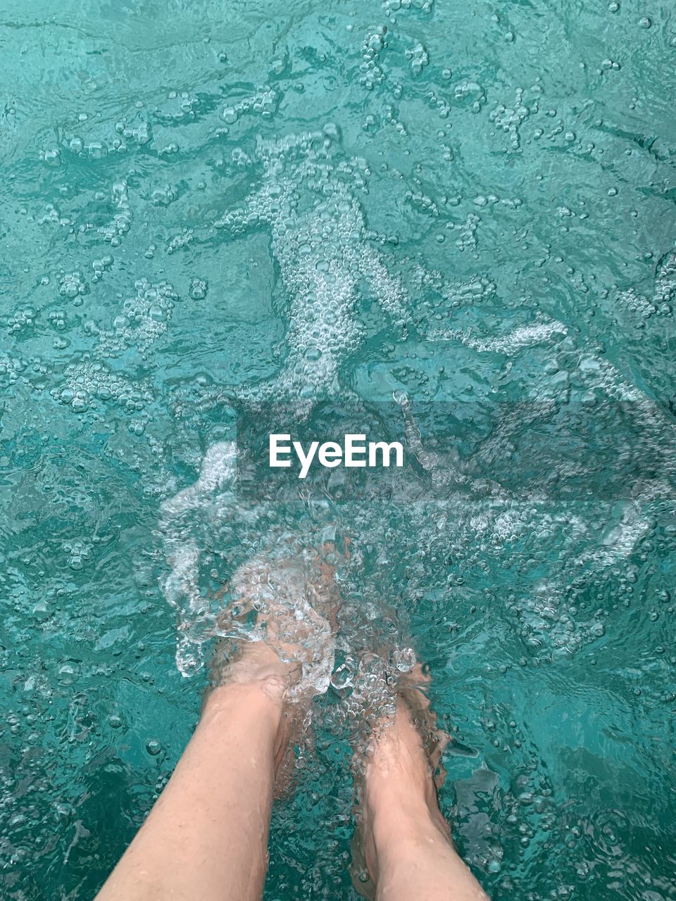 LOW SECTION OF PERSON FEET IN SWIMMING POOL