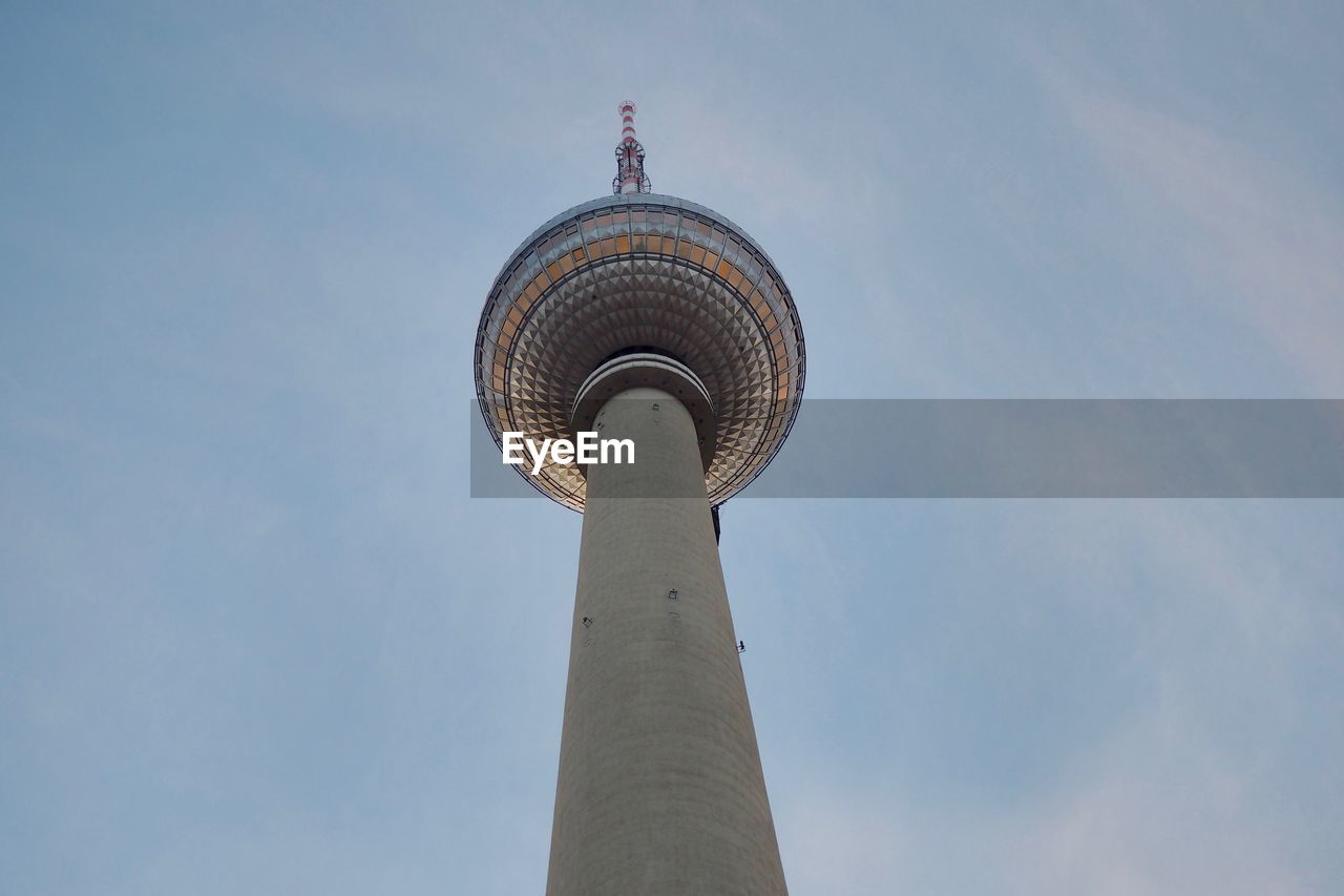 Low angle view of communications tower in city against sky