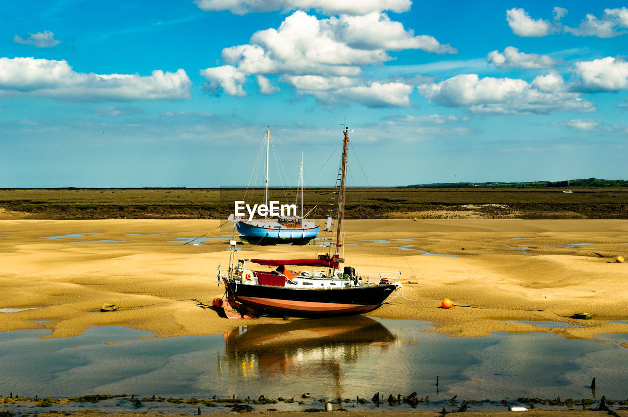 Fishing boats on shore against sky