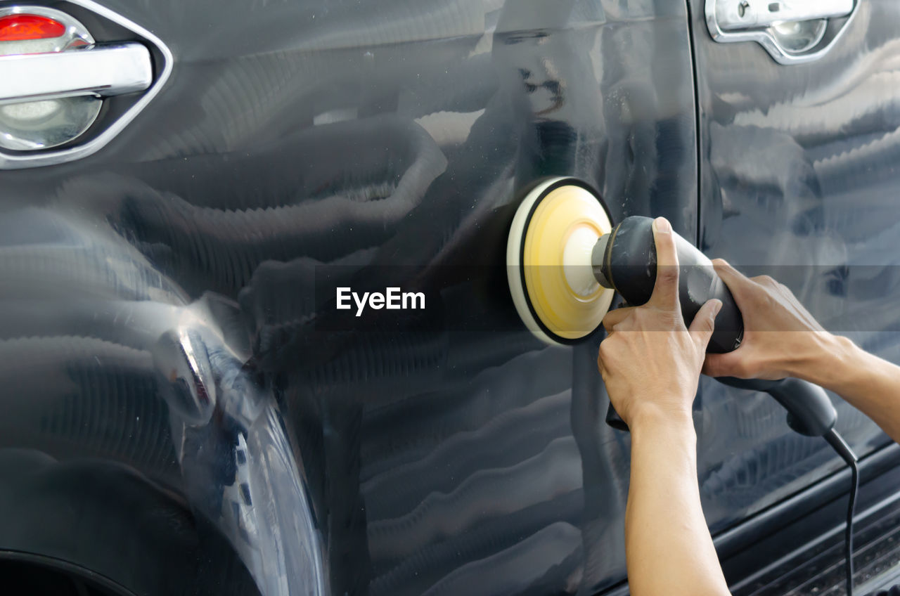 MIDSECTION OF MAN PHOTOGRAPHING CAR