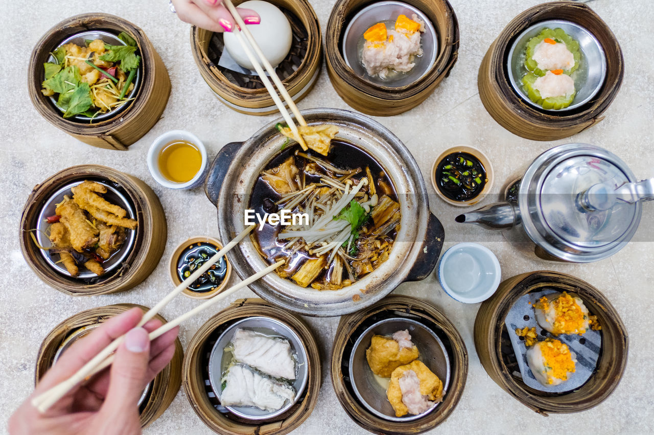 Cropped hand of people using chopstick on table