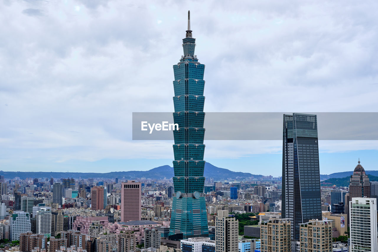 Modern buildings in city against cloudy sky