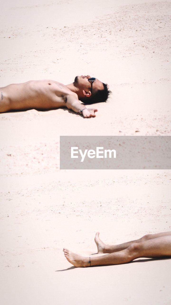 Shirtless man lying on sand