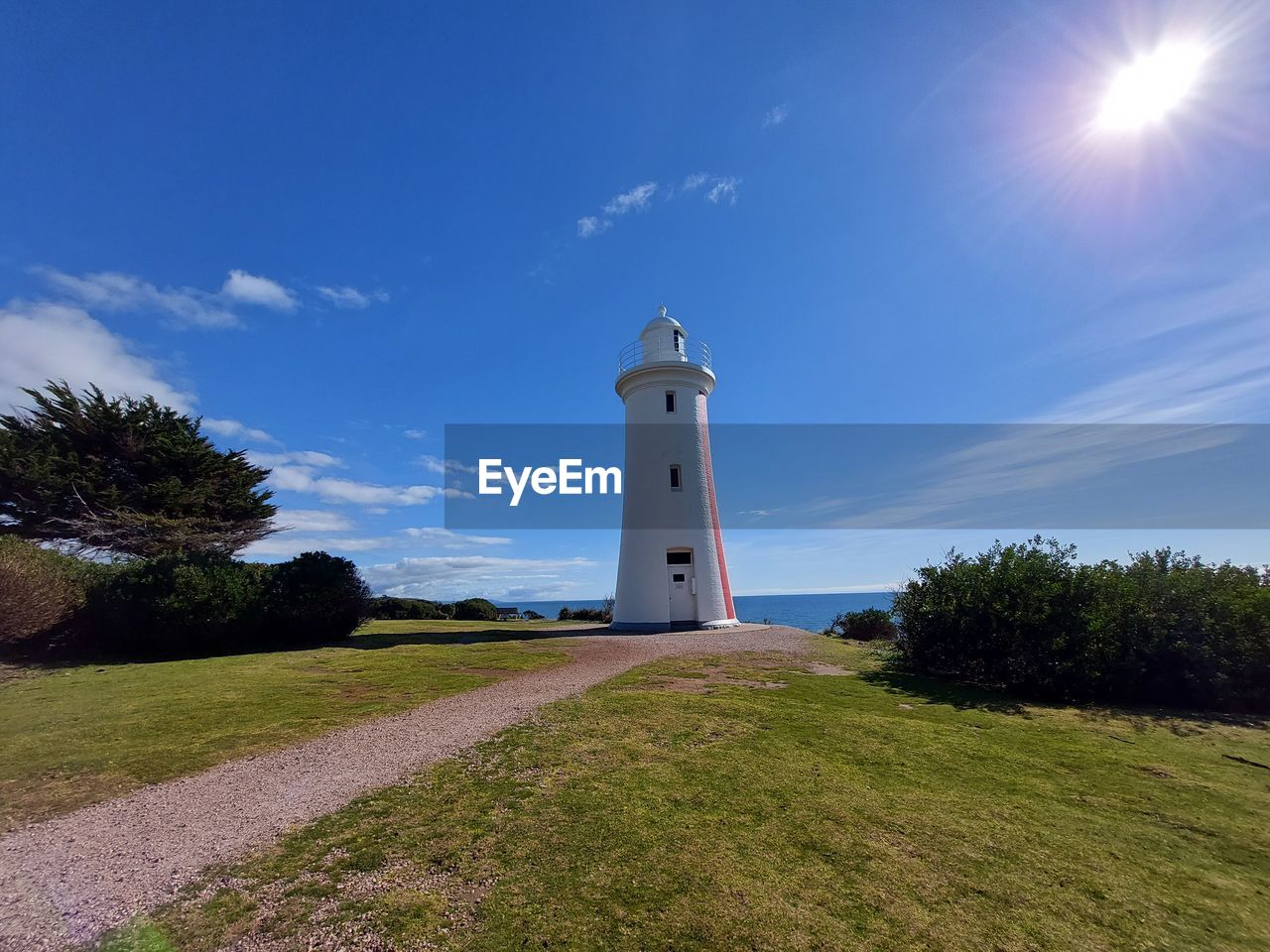 Lighthouse amidst trees and buildings against sky