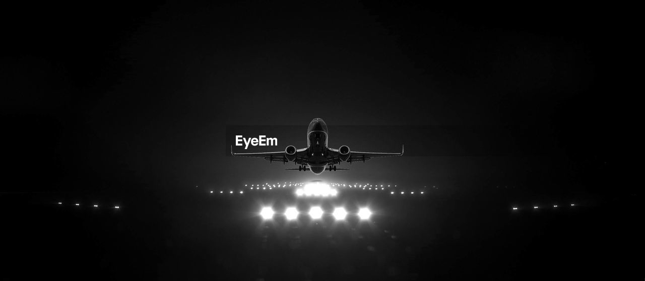 LOW ANGLE VIEW OF AIRPLANE IN SKY AT NIGHT