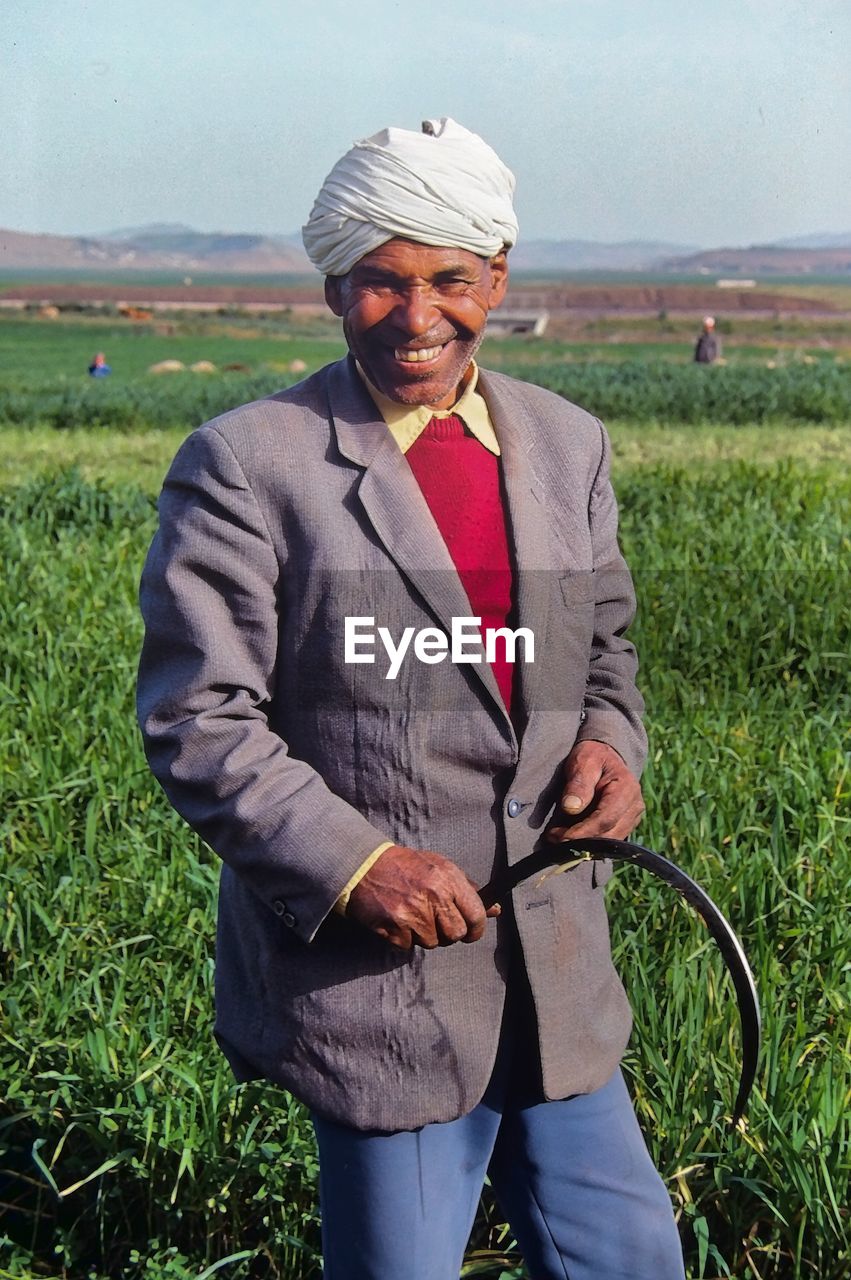 PORTRAIT OF MAN STANDING ON GRASSY FIELD