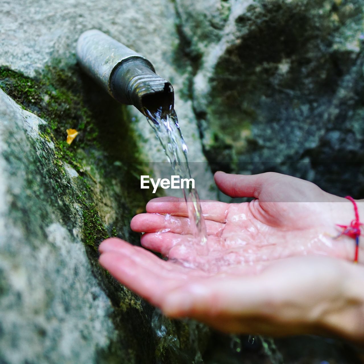 Close-up of hands holding water by fountain