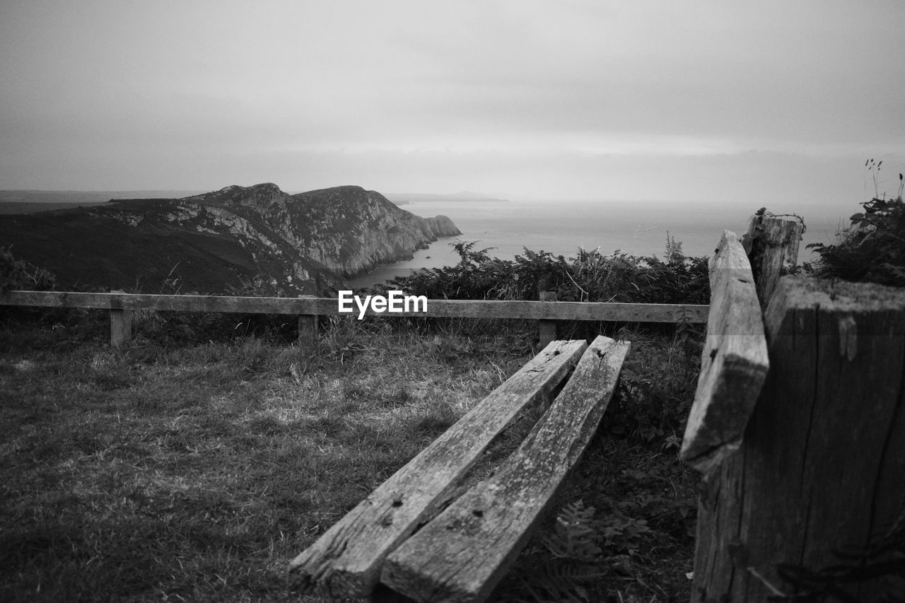 WOODEN POSTS ON FIELD AGAINST SKY