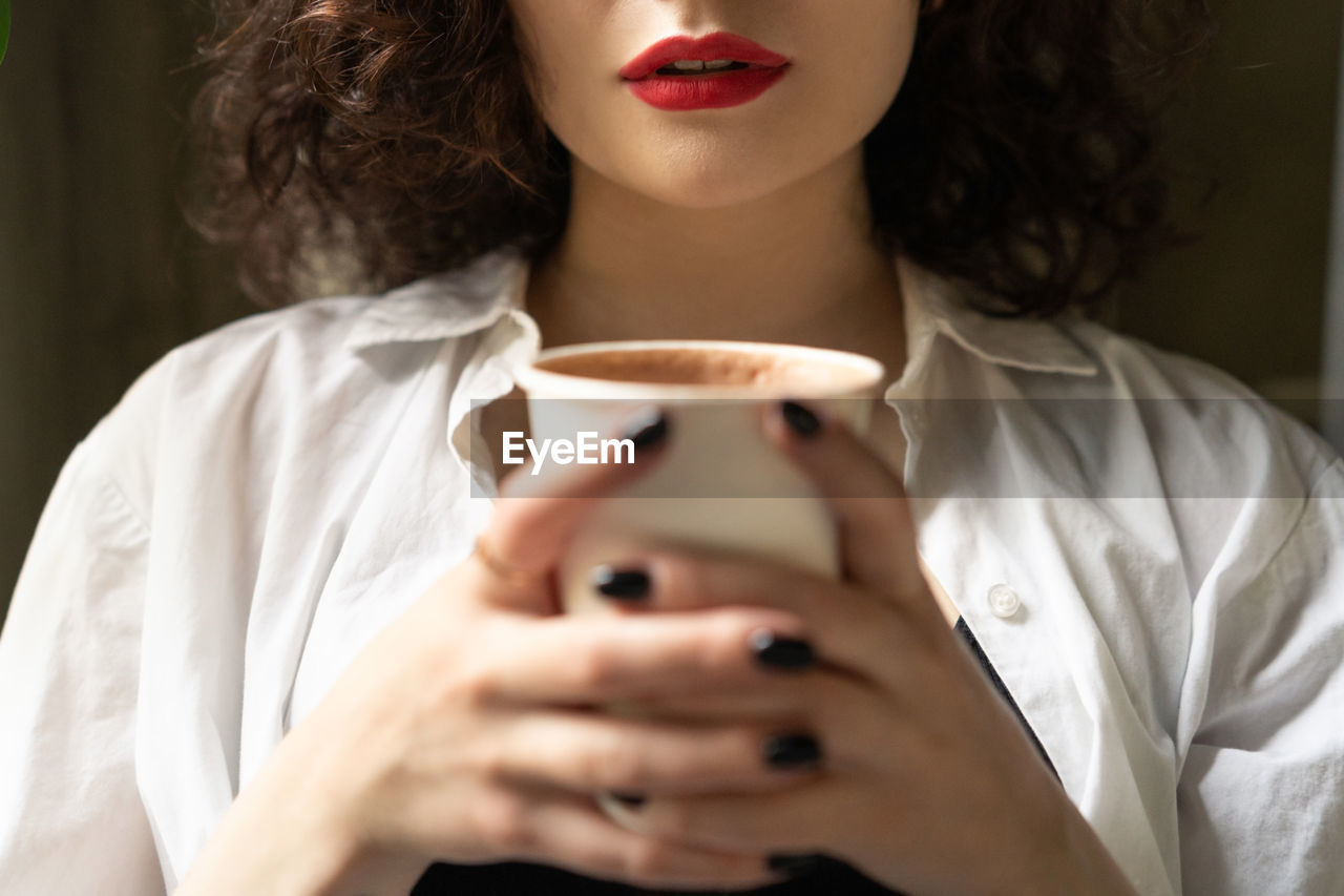 Midsection of woman drinking coffee