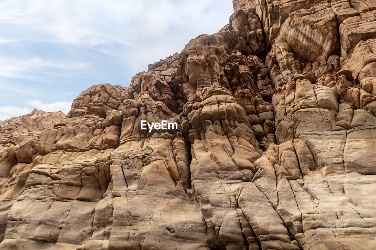 rock, rock formation, wadi, nature, arch, sky, scenics - nature, environment, beauty in nature, geology, landscape, travel destinations, land, formation, valley, mountain, cloud, no people, non-urban scene, desert, travel, ancient history, terrain, day, physical geography, outdoors, tranquility, climate, eroded, low angle view, extreme terrain, arid climate, tranquil scene, cliff, sandstone