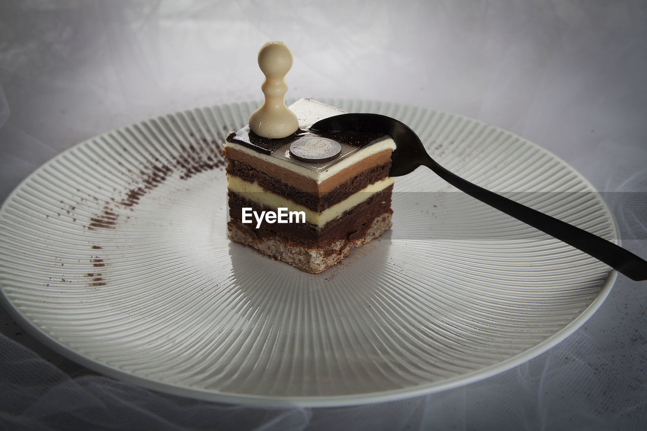 Close-up of chess piece with spoon and coin on cake in plate