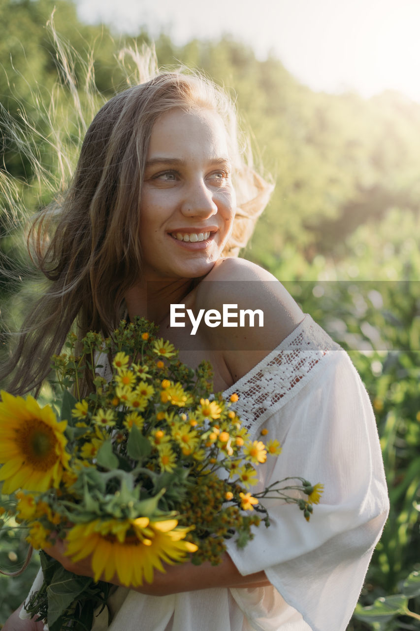 Portrait of smiling young woman against blue sky