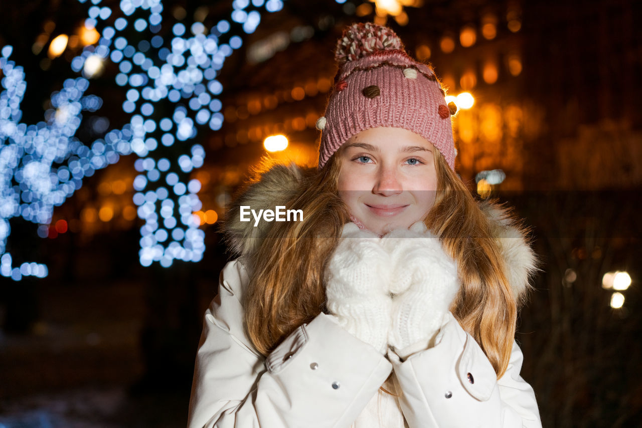 Street portrait smiling beautiful girl on festive christmas street in evening