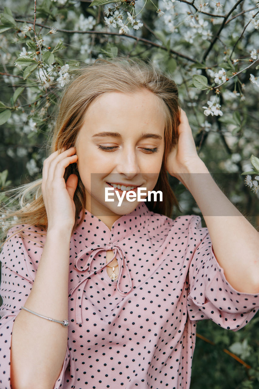 Blonde girl on a spring walk in the garden with cherry blossoms. female portrait, close-up.