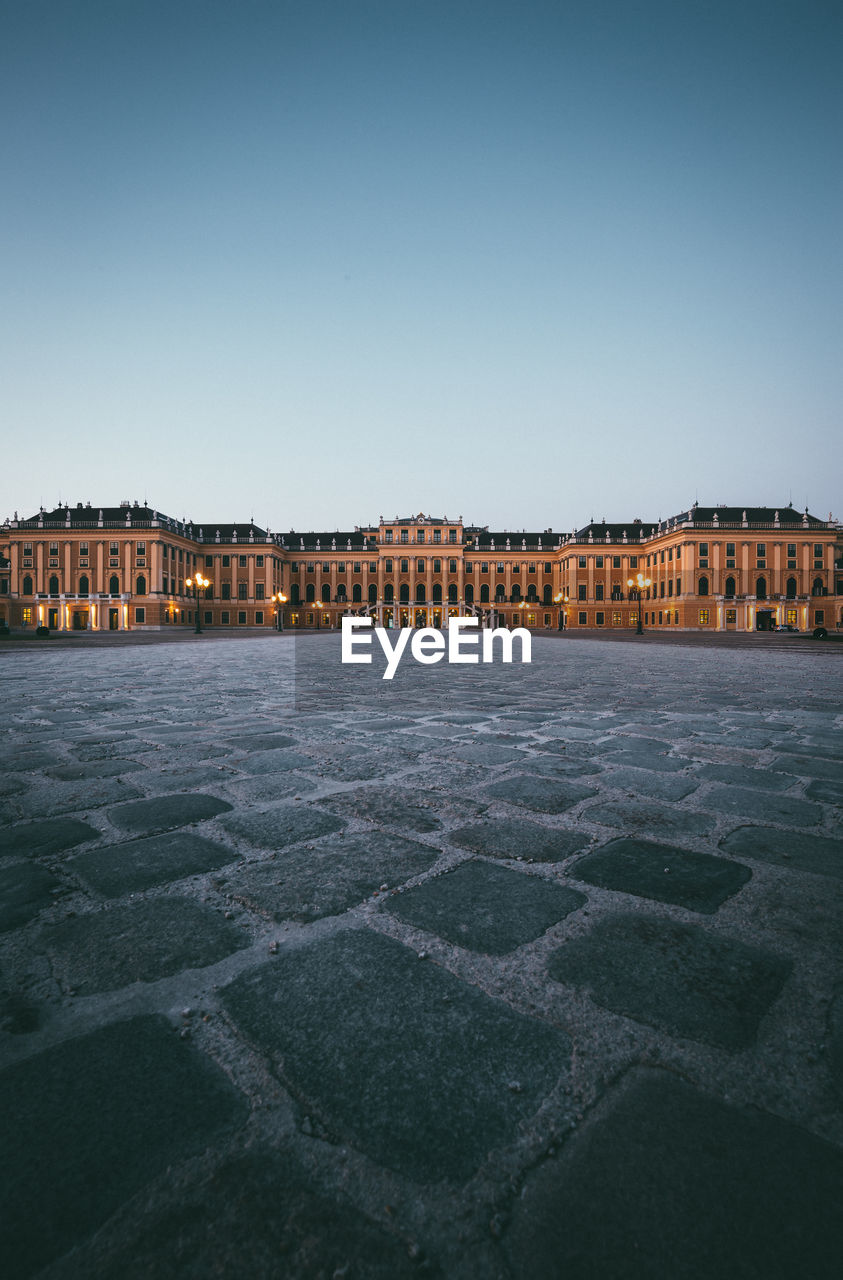 Palace building against clear sky and paving stones in the foreground