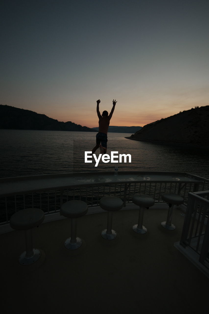 Boy jumping in sea during sunset