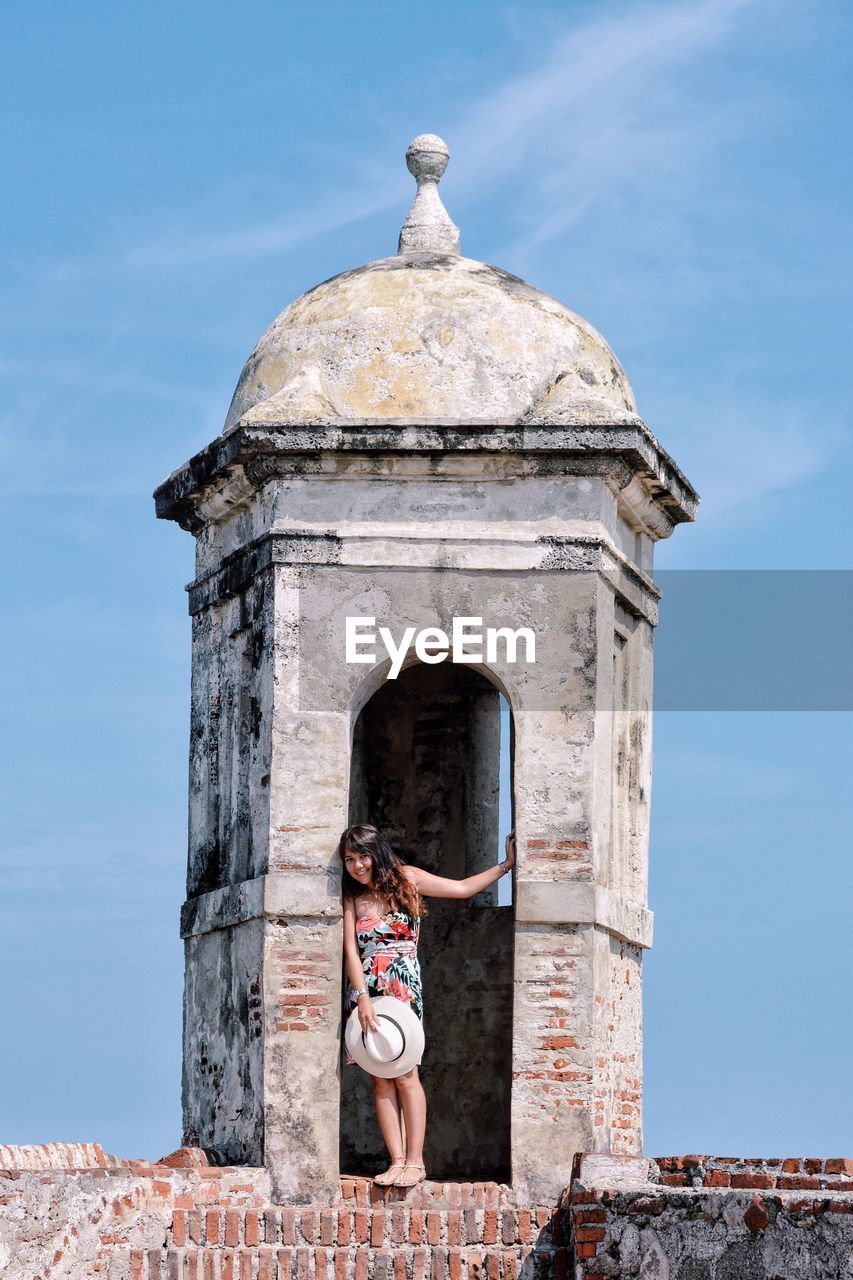 Low angle view of woman at tower against sky