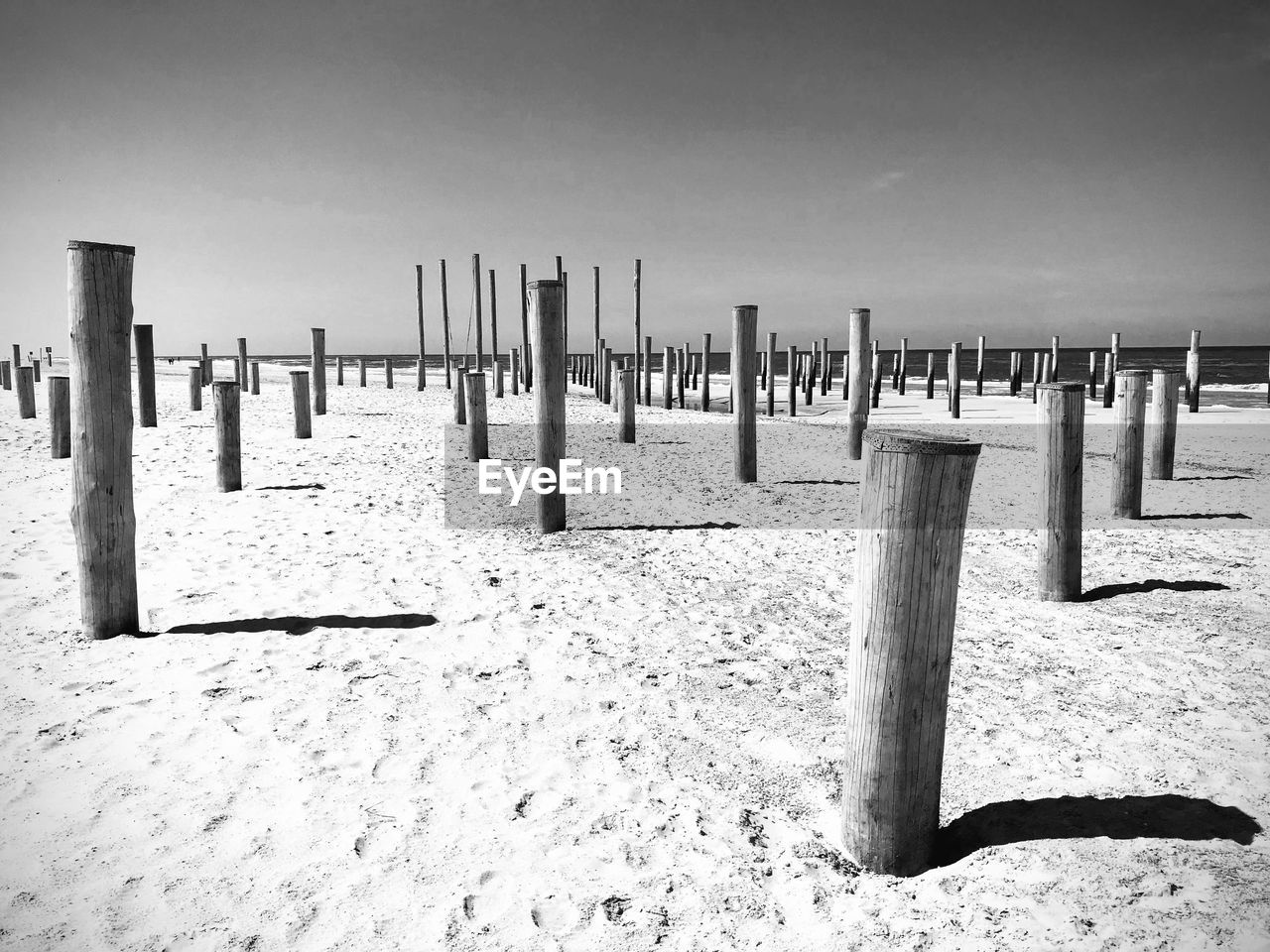 WOODEN POST ON BEACH AGAINST SKY