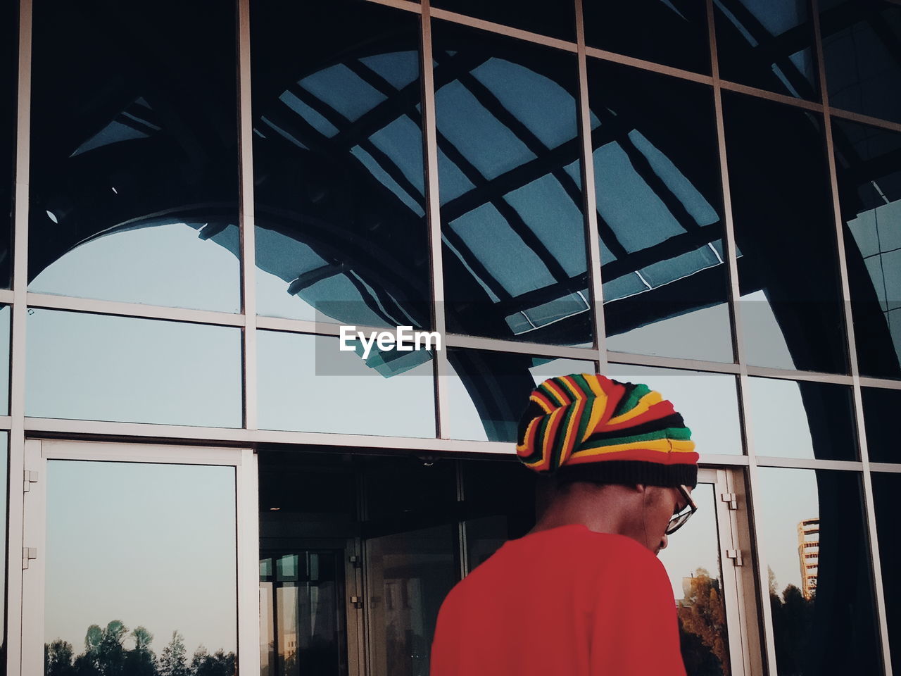 REAR VIEW OF MAN STANDING AGAINST MULTI COLORED BUILDING