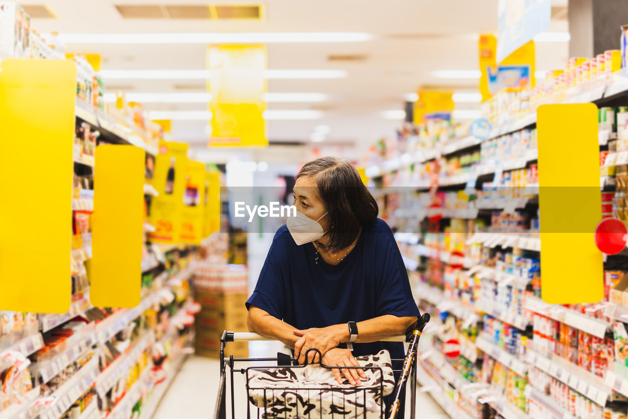 Senior woman in protective mask shopping in supermarket alone