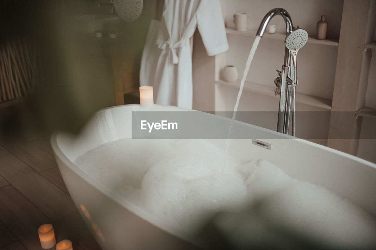 Luxury interior of big bathroom at modern african style with oval bathtub in natural lighting