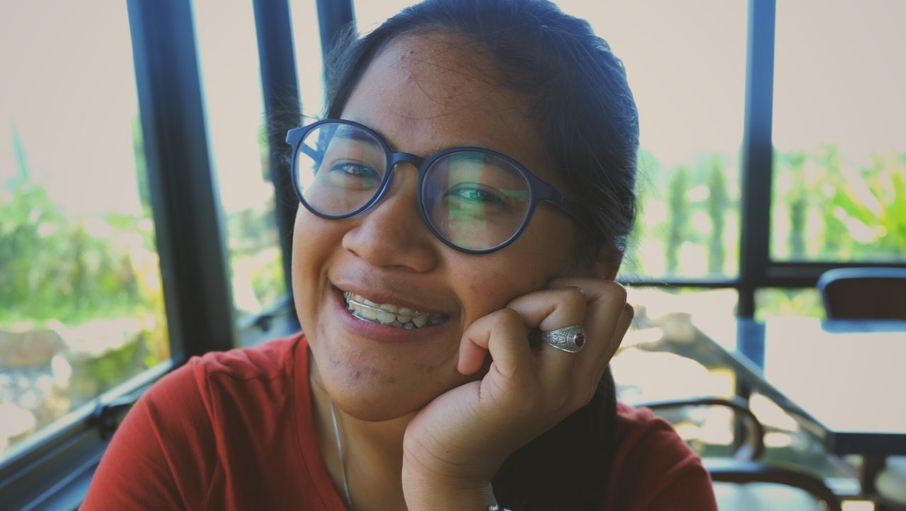 Close-up portrait of young woman smiling while sitting in cafe