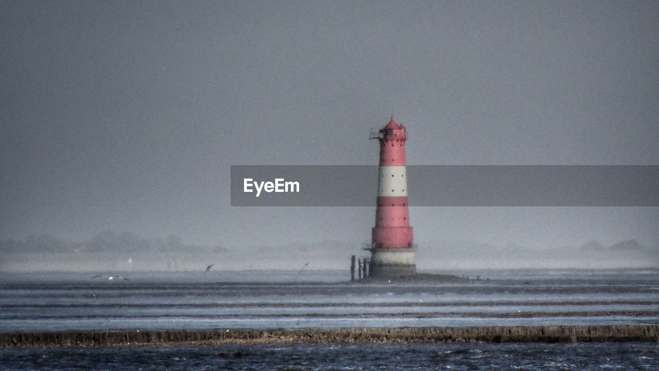 LIGHTHOUSE BY SEA AGAINST SKY AT SUNSET