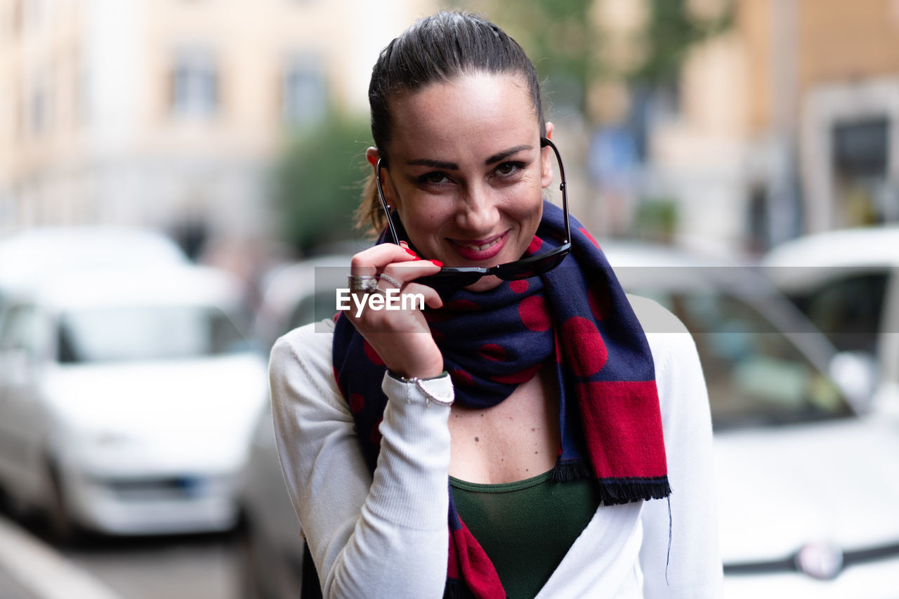 Portrait of smiling beautiful woman wearing sunglasses in city