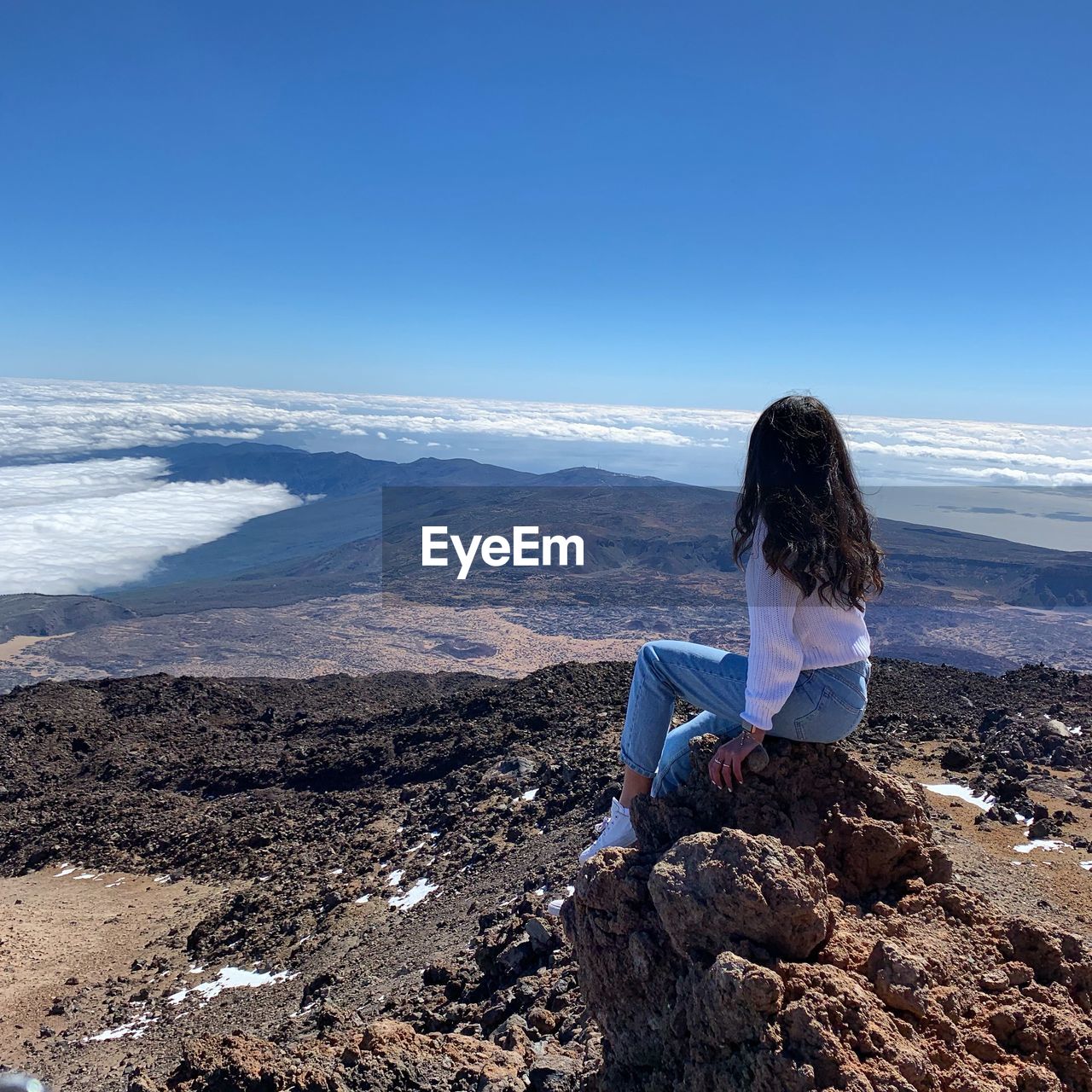 Woman sitting on rock looking 