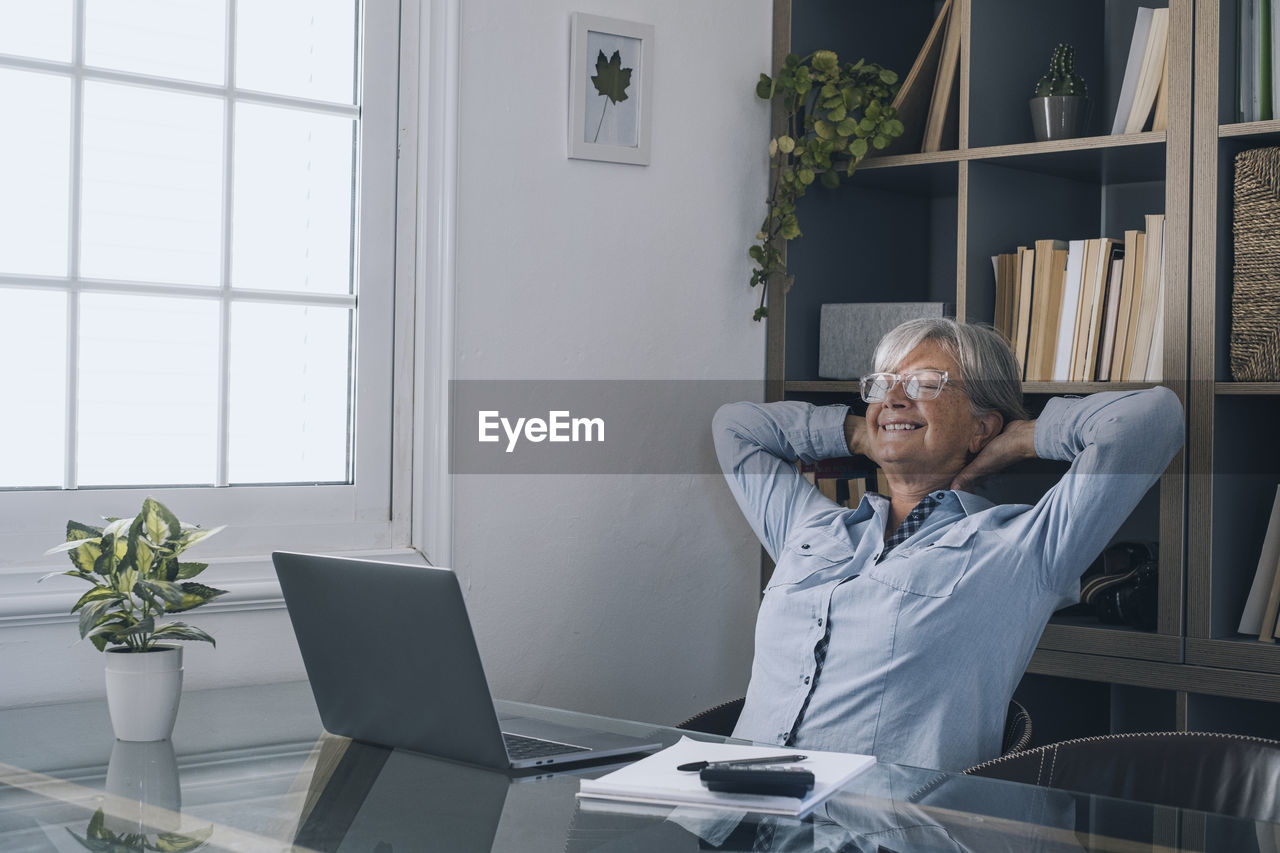 Smiling senior woman relaxing at home office