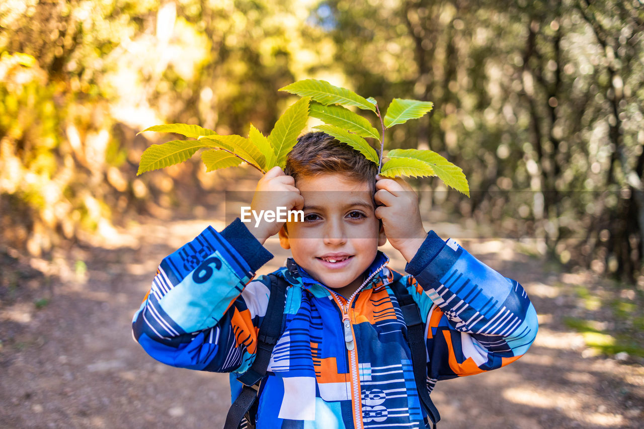 Little kid playing with leaves in autumn