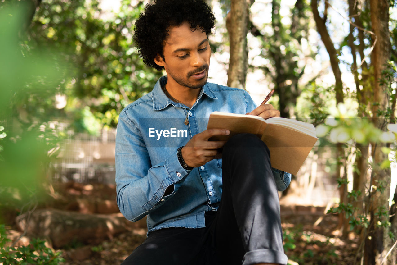 Man writing in book at park