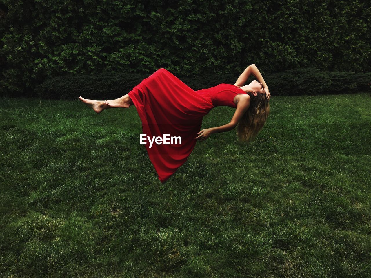 Digital composite image of woman wearing dress while lying in air over field